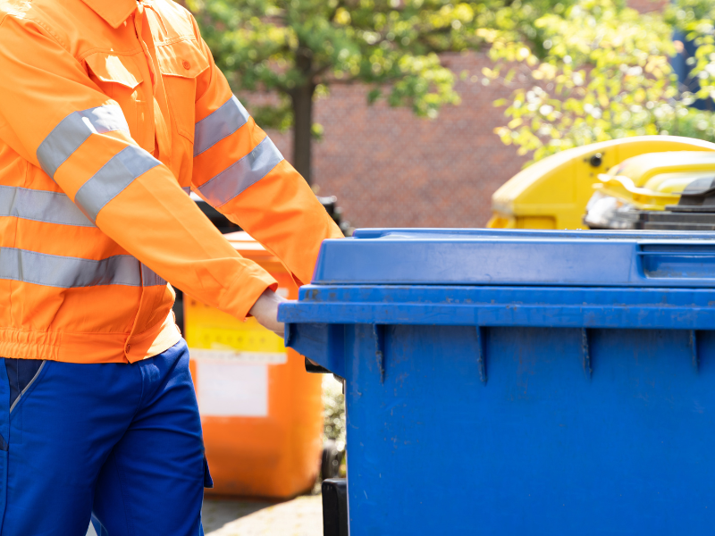Empleado recogiendo zafacón de basura en una residencia